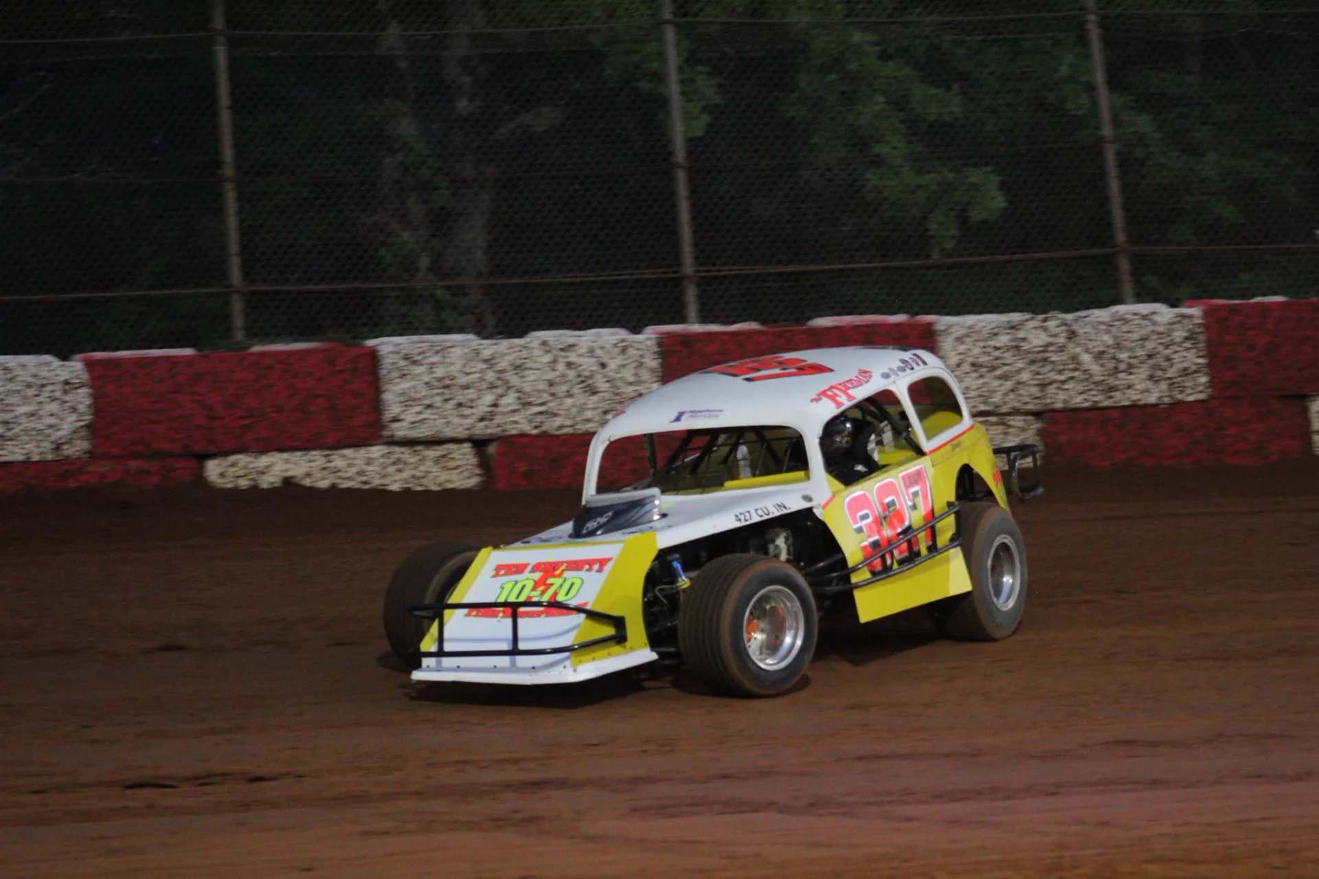 Yellow #327 vintage coupe racing under the lights